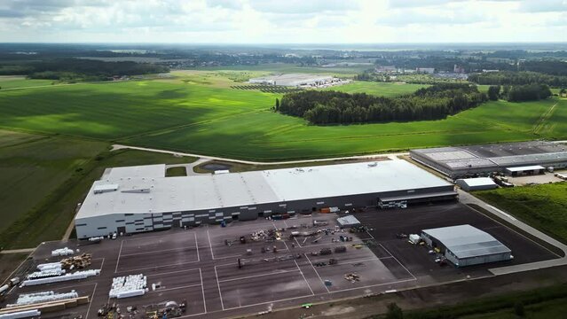 Realtime footage of a large industrial warehouse in a rural setting, from an aerial view, with expansive green fields