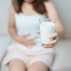 Lactose intolerance and Milk allergy concept. woman hold Milk glass and having abdominal cramps and pain when drink Cow Milk. Symptom stomach ache, Dairy intolerant, Nausea, Bloating, Gas and Diarrhea