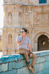 Young man wearing sunglasses and casual clothes, posing by a historic church in Oaxaca's historic center, Mexico.