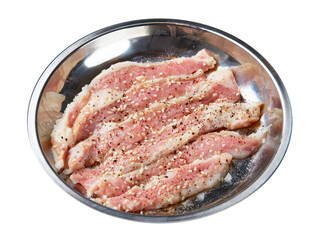 Top view of fresh pork marinated with black pepper and white sesame served served on a stainless steel tray isolated on white background.