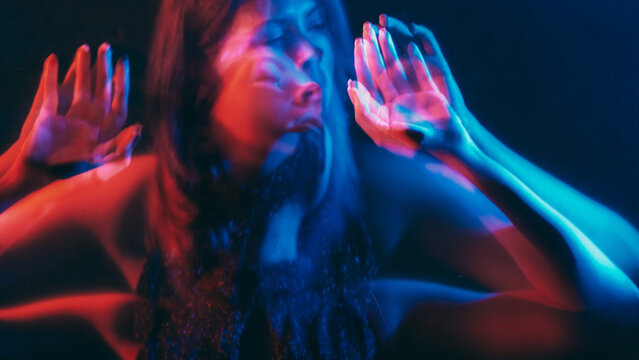 Split personality. Blur silhouette. Distracted delusional woman holding hands barrier neon red blue color dark double exposure out of focus.