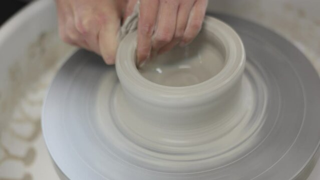 Female potter works with potter weel, craftsman hands close up. Hands of potter making clay pot. High quality 4k footage