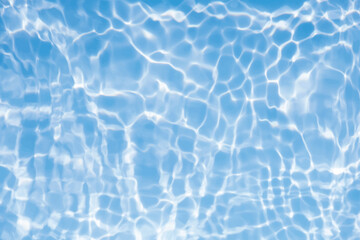 Blue water with ripples on the surface. Defocus blurred transparent blue colored clear calm water surface texture with splashes and bubbles. Water waves with shining pattern texture background.