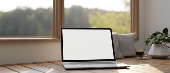 A laptop computer mockup is on a wooden bench against the window in a minimalist living room.