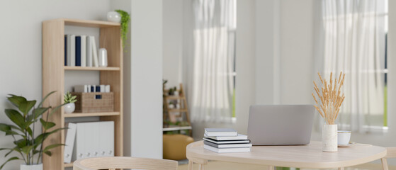 A laptop computer, books, and decor on a wooden table in a contemporary, minimalist living room.