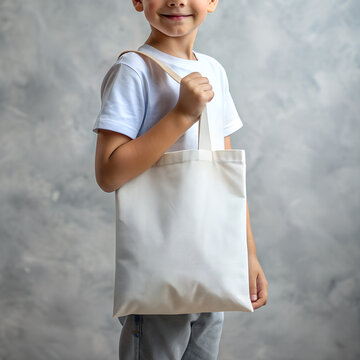 Tote bag mockup. Smiling boy carrying reusable white cotton eco organic fabric canvas blank totebag on grey background. AI generated