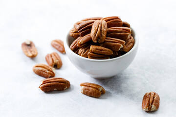Pecan nuts in a white bowl.