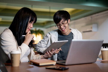 Fototapeta premium A young Asian female college student is explaining something on her digital tablet to her friend.