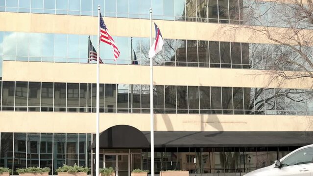 American and North Carolina state flags waving outside a modern building, reflecting patriotism and state pride on a sunny day.