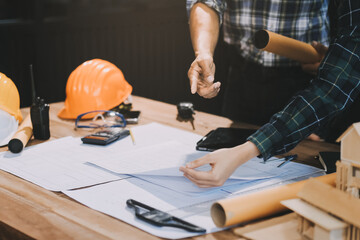 Asian young female architect discussing with japanese male building manager contractor for quality control site inspection and at house construction site in room under renovation project.