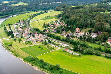 Naklejka premium A small town with a river running through it. The houses are small and spread out. The grass is green and the sky is cloudy
