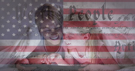 American flag and constitution text against caucasian girl kissing her mother under a blanket