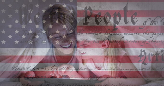 American flag and constitution text against caucasian girl kissing her mother under a blanket - Powered by Adobe