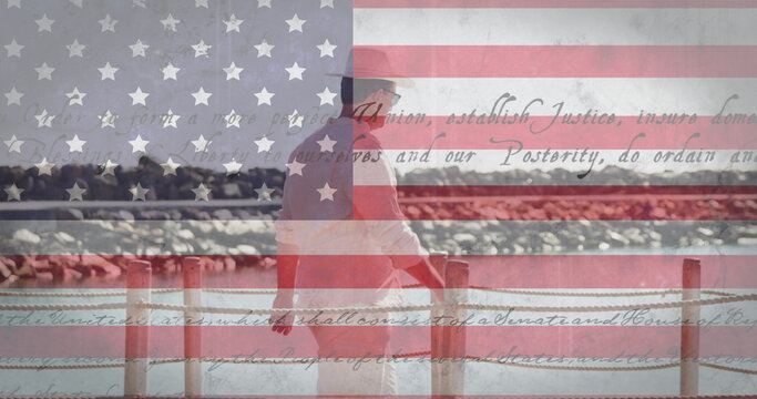 Image of man walking on jetty over american flag and constitution text - Powered by Adobe