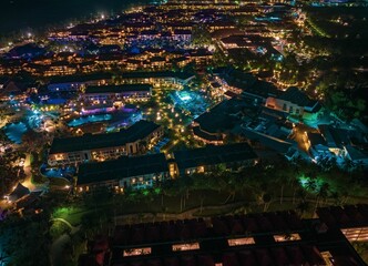 Aerial view of a vibrant resort at night with illuminated buildings and pools
