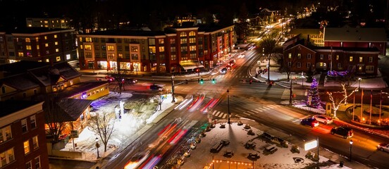 Aerial view of a busy intersection in a small town at night with light trails from moving cars.