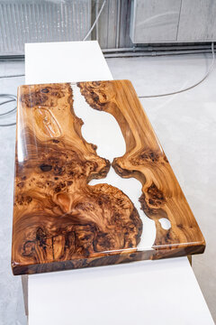 Live edge elm burl slab table top with central epoxy resin river on sawhorses in professional workshop