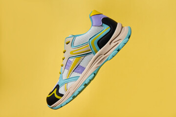 Single colorful sport sneaker isolated on yellow background. Stylish fashionable sport shoe