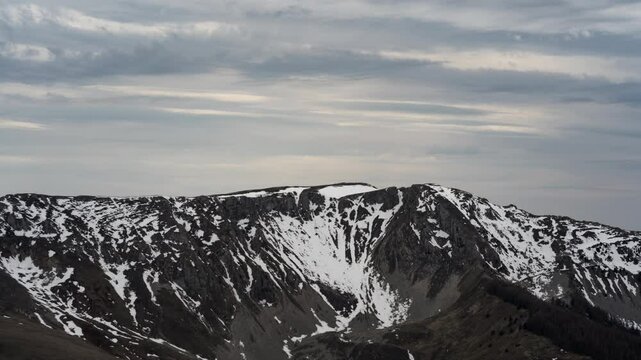 Timelapse of Des Monges mountain as snowy peaks during sunset or sunrise. Majestic snowy terrain in alpine alps with sky and clouds in time lapse as natural scenery. Snowy peaks and landscapes France