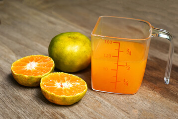 fresh orange juice with orange on wood table . orange fruit  . Natural orange juice in measuring cup . 