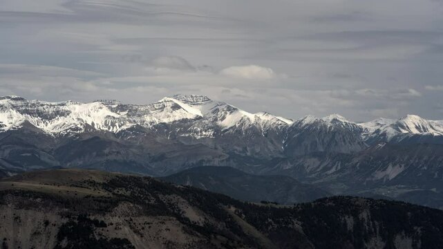 Timelapse of Des Monges mountain as snowy peaks during sunset or sunrise. Majestic snowy terrain in alpine alps with sky and clouds in time lapse as natural scenery. Snowy peaks and landscapes France