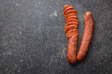 Sliced smoked salami sausage on black table. Top view.