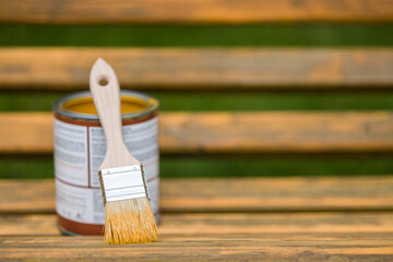 Paint Brush and Can on a Wooden Bench Outdoors