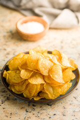 Crispy Potato Chips on plate on kitchen table.
