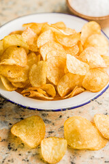Crispy Potato Chips in bowl on kitchen table.