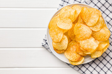 Crispy Potato Chips on plate on white table. Top view.