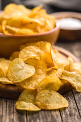 Crispy Potato Chips on cutting board on wooden table.