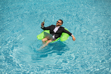 Successful business man in suit in pool water. Business man in suit working on laptop in swimming pool. Travel tourism and business concept. Crazy male office business employee using laptop.