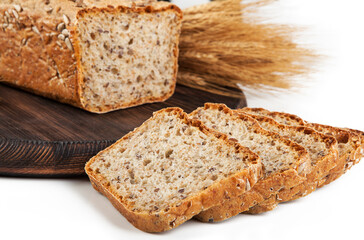 Freshly baked bread on wooden cutting board with ears of wheat.