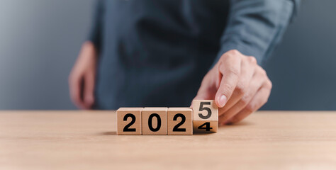 businessman hand assemble wooden block cube to status from 2024 to 2025 new year. goals trends 2025...