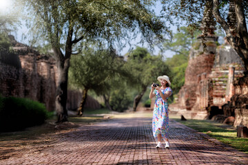 Young woman traveling in temple, Asian traveler take a photo temple in Ayutthaya Historical Park UNESCO World Heritage Site.Asian female tourist taking pictures at Wat Phra Si Sanphet in Ayutthaya