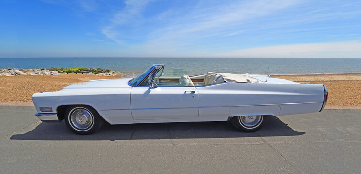 Classic White Cadillac De Ville Convertible  Motor parked on seafront Beach and Sea in Background