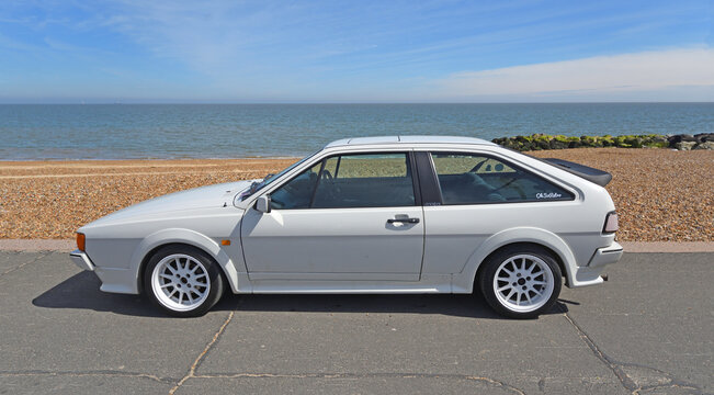 Classic VW Scirocco in  White  parked on seafront beach and sea in background