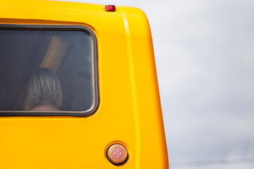 Back of ladies head through yellow bus window against a cloudy sky - theme on travel 