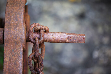 Brown rusty iron chain hanging on rusty holder against a natural background 