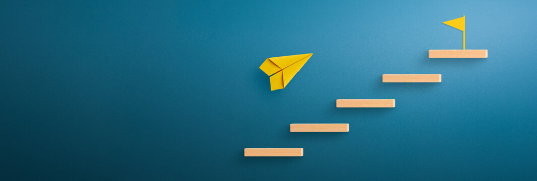 Wooden block stacking as step stair with yellow paper plane and flag target icon, Ladder of success in business growth concept