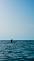 Fototapeta premium silhouette of person doing sup surfing on the sunset in the blue sea