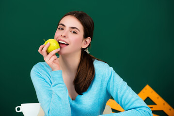 Student girl eat apple in school class. The student girl works hard to understand the material. Student teenager learning in the classroom. The student girl is in class at school.