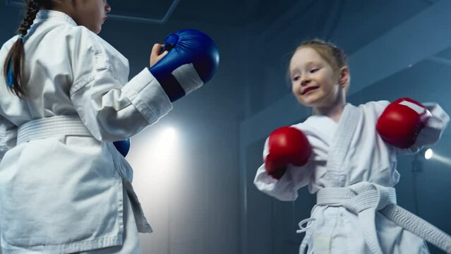 Little girls practicing karate. Females in white kimono sparring. Healthy kids. Focused girls training karate and practice fight technique. Sport concept. 4K, UHD