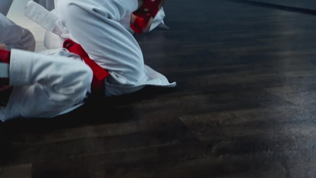 Boys practicing karate in smoky room. Group of children sparring together. Sporty childhood. Aggressive attack with leg kicks. Little children in white kimono training karate. 4K, UHD
