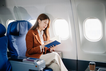 ￼Asian woman sitting in a seat in airplane and looking out the window going on a trip vacation travel concept.Capture the allure