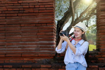 Young woman traveling in temple, Asian traveler take a photo temple in Ayutthaya Historical Park UNESCO World Heritage Site.Asian female tourist taking pictures at Wat Phra Si Sanphet in Ayutthaya