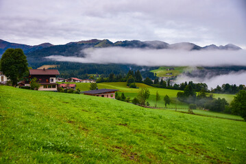 Morning mist rising over Alpine valley in autumn colorful countryside
