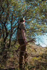 Scout searching for antlers in a holm oak forest with a deer antler in his hand.