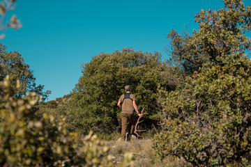 Hunter walking in the bush with a deer antler in his hand.