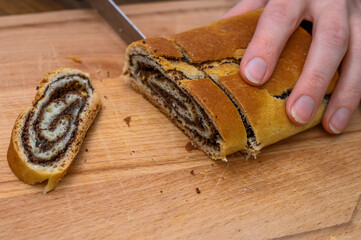 Makowiec, świąteczne ciasto drożdżowe z makiem krojone na deskę do krojenia z bliska